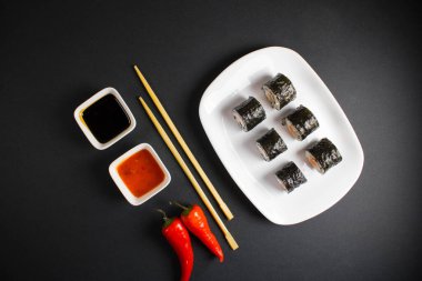 Koyu bir arka planda bir suşi rulosu servis edilir. Suşili lezzetli geleneksel Japon yemekleri..