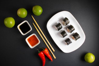 Koyu bir arka planda bir suşi rulosu servis edilir. Suşili lezzetli geleneksel Japon yemekleri..