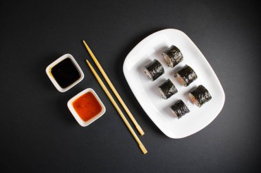 Koyu bir arka planda bir suşi rulosu servis edilir. Suşili lezzetli geleneksel Japon yemekleri..