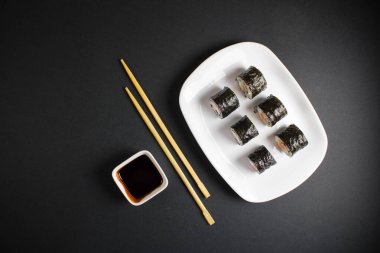 Koyu bir arka planda bir suşi rulosu servis edilir. Suşili lezzetli geleneksel Japon yemekleri..