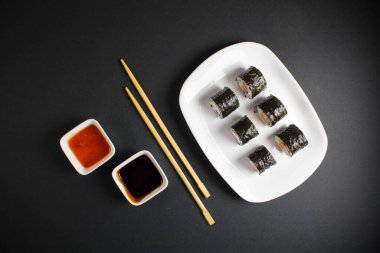 Koyu bir arka planda bir suşi rulosu servis edilir. Suşili lezzetli geleneksel Japon yemekleri..