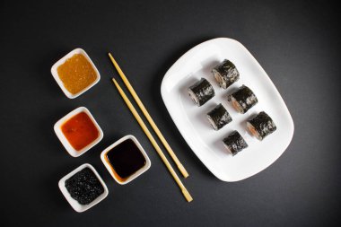 Koyu bir arka planda bir suşi rulosu servis edilir. Suşili lezzetli geleneksel Japon yemekleri..