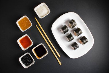 Koyu bir arka planda bir suşi rulosu servis edilir. Suşili lezzetli geleneksel Japon yemekleri..