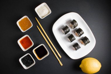 Koyu bir arka planda bir suşi rulosu servis edilir. Suşili lezzetli geleneksel Japon yemekleri..