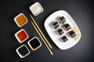 Koyu bir arka planda bir suşi rulosu servis edilir. Suşili lezzetli geleneksel Japon yemekleri..