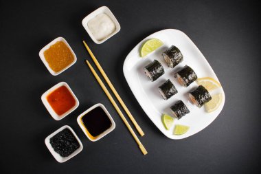 Koyu bir arka planda bir suşi rulosu servis edilir. Suşili lezzetli geleneksel Japon yemekleri..