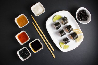 Koyu bir arka planda bir suşi rulosu servis edilir. Suşili lezzetli geleneksel Japon yemekleri..