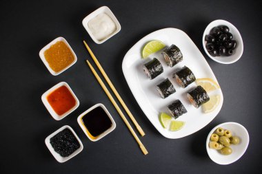 Koyu bir arka planda bir suşi rulosu servis edilir. Suşili lezzetli geleneksel Japon yemekleri..