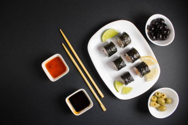 Koyu bir arka planda bir suşi rulosu servis edilir. Suşili lezzetli geleneksel Japon yemekleri..