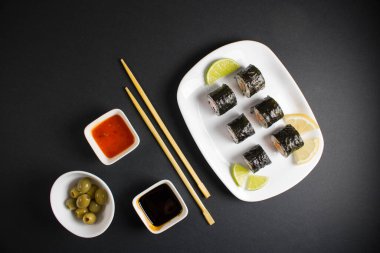 Koyu bir arka planda bir suşi rulosu servis edilir. Suşili lezzetli geleneksel Japon yemekleri..