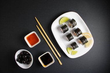 Koyu bir arka planda bir suşi rulosu servis edilir. Suşili lezzetli geleneksel Japon yemekleri..