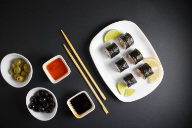 Koyu bir arka planda bir suşi rulosu servis edilir. Suşili lezzetli geleneksel Japon yemekleri..