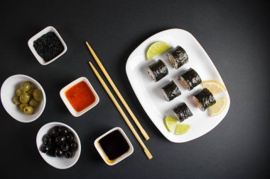 Koyu bir arka planda bir suşi rulosu servis edilir. Suşili lezzetli geleneksel Japon yemekleri..