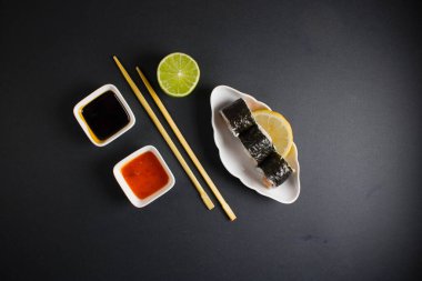 Koyu bir arka planda bir suşi rulosu servis edilir. Suşili lezzetli geleneksel Japon yemekleri..