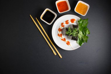 Koyu bir arka planda bir suşi rulosu servis edilir. Suşili lezzetli geleneksel Japon yemekleri..