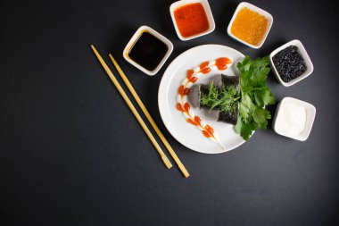 Koyu bir arka planda bir suşi rulosu servis edilir. Suşili lezzetli geleneksel Japon yemekleri..