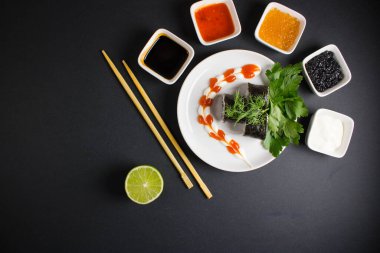 Koyu bir arka planda bir suşi rulosu servis edilir. Suşili lezzetli geleneksel Japon yemekleri..