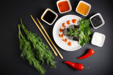 Koyu bir arka planda bir suşi rulosu servis edilir. Suşili lezzetli geleneksel Japon yemekleri..