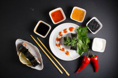 Koyu bir arka planda bir suşi rulosu servis edilir. Suşili lezzetli geleneksel Japon yemekleri..