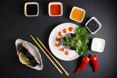 Koyu bir arka planda bir suşi rulosu servis edilir. Suşili lezzetli geleneksel Japon yemekleri..