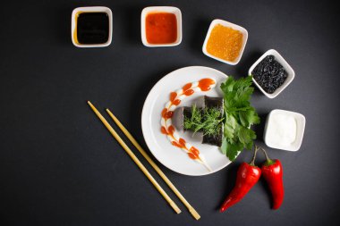 Koyu bir arka planda bir suşi rulosu servis edilir. Suşili lezzetli geleneksel Japon yemekleri..