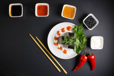 Koyu bir arka planda bir suşi rulosu servis edilir. Suşili lezzetli geleneksel Japon yemekleri..