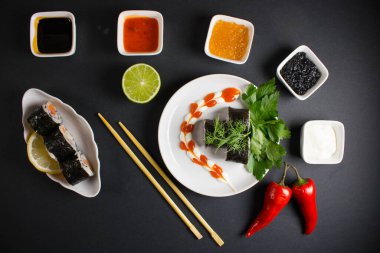 Koyu bir arka planda bir suşi rulosu servis edilir. Suşili lezzetli geleneksel Japon yemekleri..