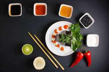 Koyu bir arka planda bir suşi rulosu servis edilir. Suşili lezzetli geleneksel Japon yemekleri..
