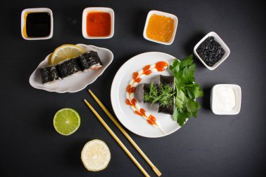 Koyu bir arka planda bir suşi rulosu servis edilir. Suşili lezzetli geleneksel Japon yemekleri..