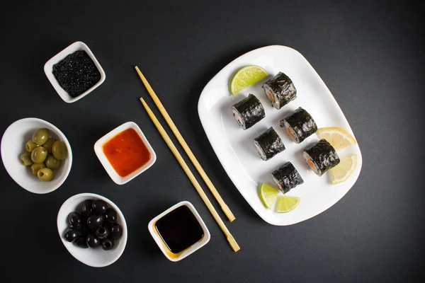 Koyu bir arka planda bir suşi rulosu servis edilir. Suşili lezzetli geleneksel Japon yemekleri..