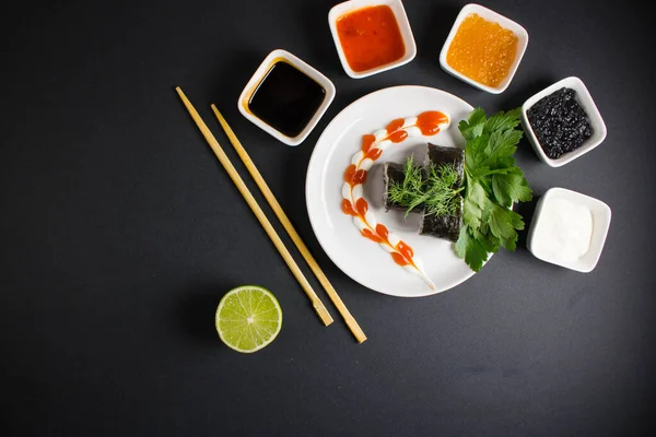 Koyu bir arka planda bir suşi rulosu servis edilir. Suşili lezzetli geleneksel Japon yemekleri..