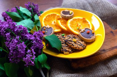 Sarı tabakta dilimlenmiş portakal ve bisküvi.