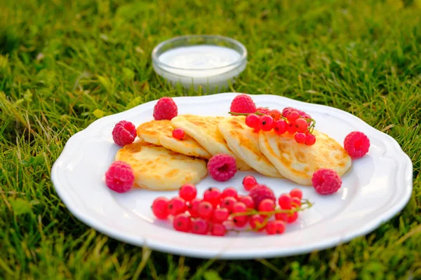 Delicious curd pancakes with raspberries red currants and sour cream — Stock Photo, Image