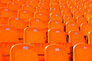 Satırlar bir stadyumda boş parlak oranje plastik koltuklar