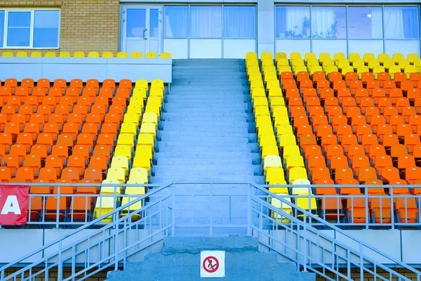 Schodiště a sportovní tribun oranžových a žlutých sedadel. — Stock fotografie