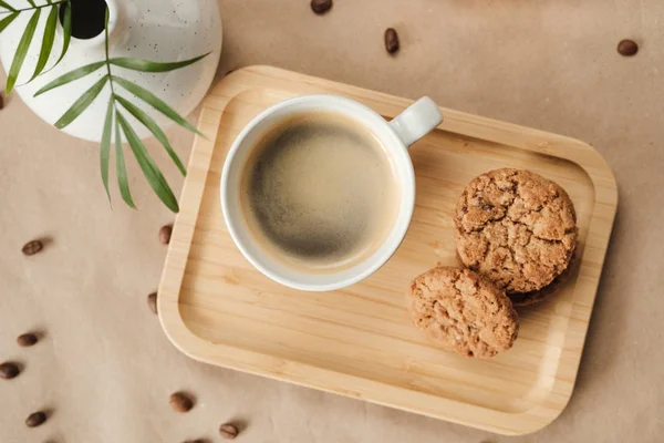 Coffee and oatmeal cookies on a wooden tray next to a vase — Stock Photo, Image