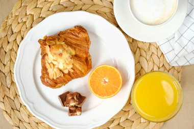 çikolata parçaları ile kruvasan, kapuçino, portakal suyu ve yarım mandalina