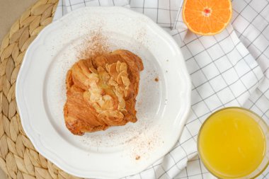 portakal suyu ve yarım mandalina ile tarçın serpilir badem yaprakları ile kruvasan