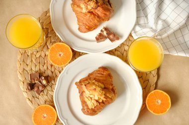 Kahvaltı kruvasan, çikolata parçaları, portakal suyu ve mandalina ile servis edilir.