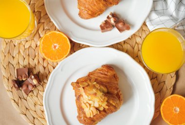 Kahvaltı kruvasan, çikolata parçaları, portakal suyu ve mandalina ile servis edilir.