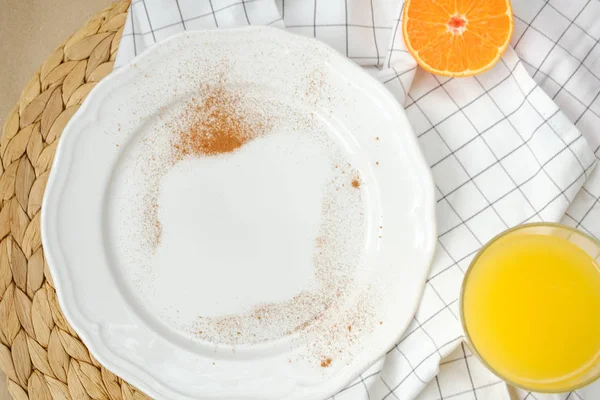 Порожня тарілка, посипана корицею, склянкою апельсинового соку і половиною мандарина — стокове фото