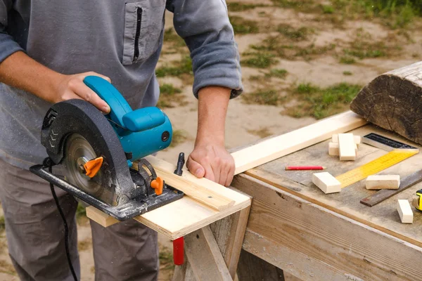 Working circular saw. a man is sawing a tree. men's hands and construction tools — Stock Photo, Image