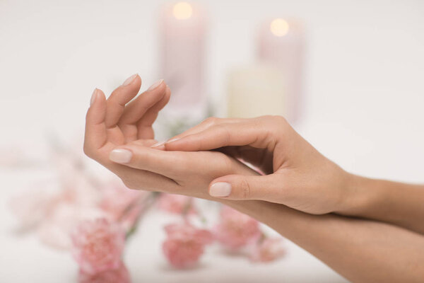 Manicure. Beautiful and delicate hands on white background with pink flowers.