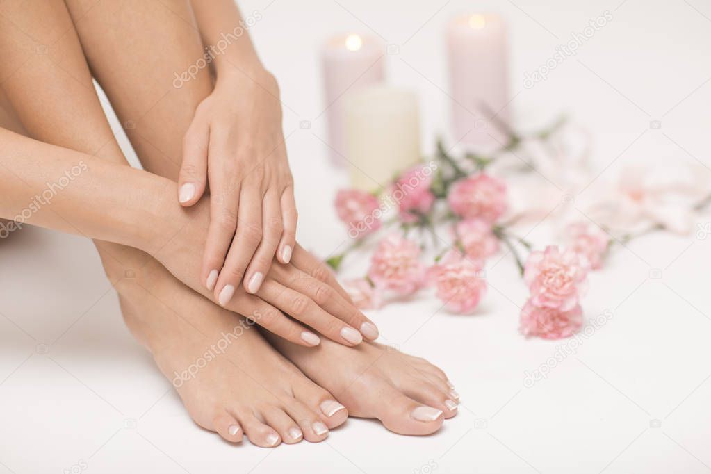 The picture of ideal done manicure and pedicure. Female hands and legs in the spa spot.