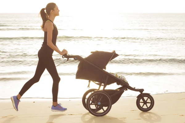 Młoda Mama Jest Uruchomiona Wózka Plaży — Zdjęcie stockowe