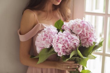 Beautiful woman holding a pink hydrangeas in her arms.  clipart