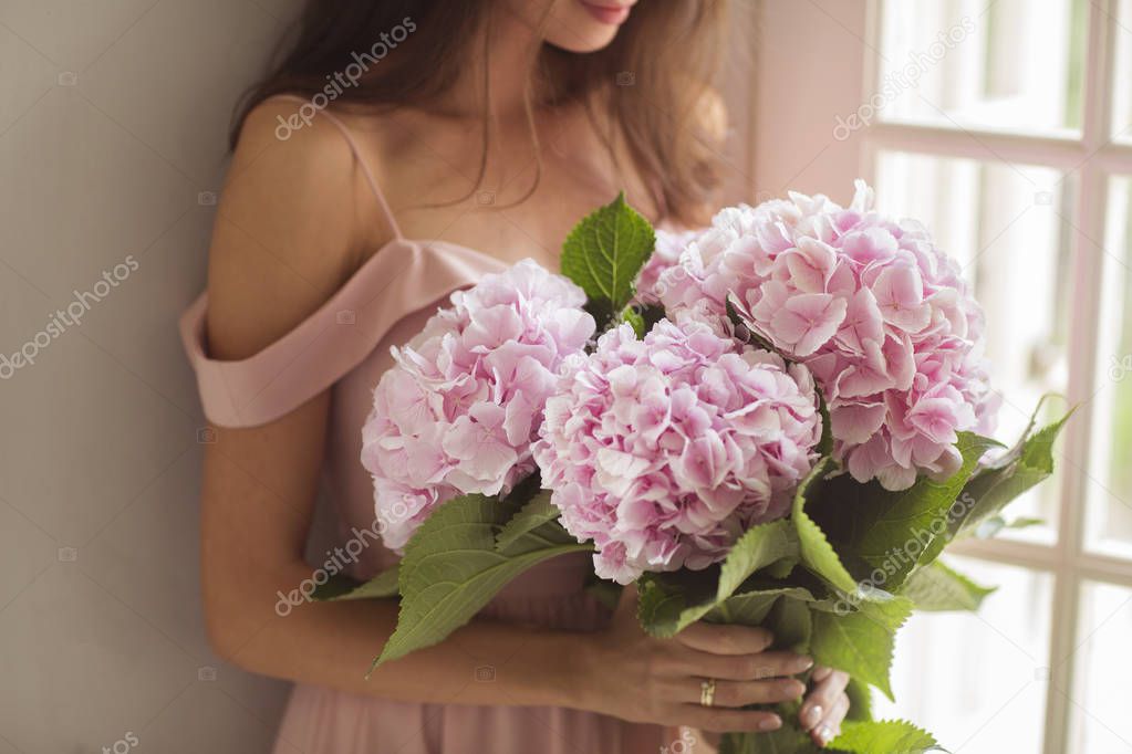 Beautiful woman holding a pink hydrangeas in her arms. 