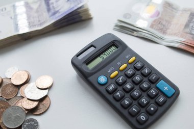 İngiliz para birimi ve hesap makinesi masada, sayma bekliyor.