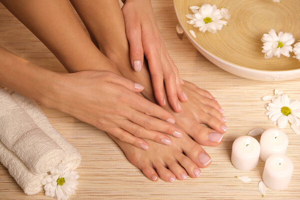 The picture of ideal done manicure and pedicure. Female hands and legs in the spa spot.