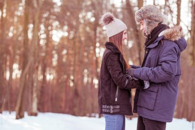 Genç çift ormanda kış boyunca yürüyor. Romantik yürüyüş için güzel sahne